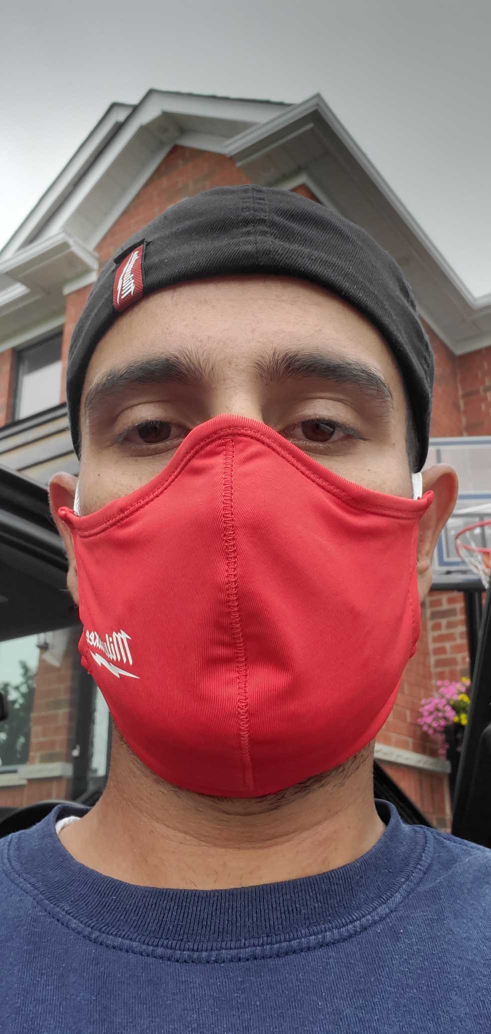 Man looking into camera for a selfie wearing a red mask to protect himself from COVID-19.